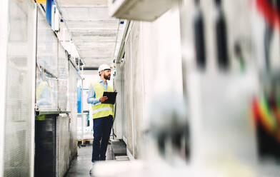 Porträt eines reifen Industrieingenieurs mit Klemmbrett in einer Fabrik, bei der Arbeit. Raum kopieren. - HPIF29550