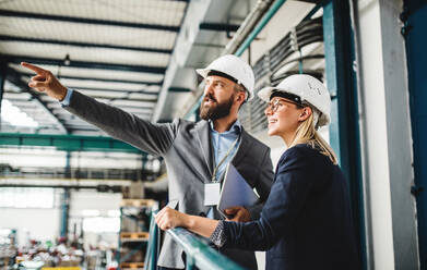 Porträt eines reifen Industriellen und einer Ingenieurin mit Tablet in einer Fabrik bei der Arbeit. - HPIF29570