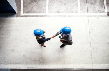 A top view of an industrial man and woman engineer in a factory, shaking hands. Copy space. - HPIF29576
