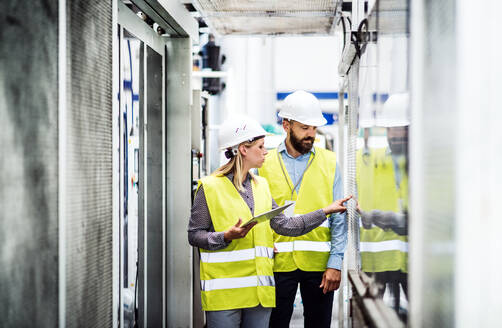 Porträt eines reifen Industriellen und einer Ingenieurin mit Tablet in einer Fabrik bei der Arbeit. - HPIF29579