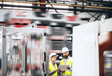 Porträt eines reifen Industriellen und einer Ingenieurin mit Tablet in einer Fabrik bei der Arbeit. - HPIF29586