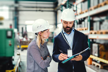 Ein Porträt eines ernsten, reifen Industriemannes und einer Ingenieurin mit Klemmbrett in einer Fabrik. - HPIF29590