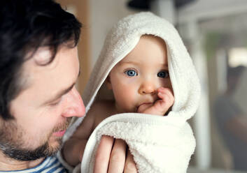Father with an happy toddler child wrapped in a towel in a bathroom at home. Paternity leave. Close up. - HPIF29636