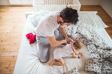 Vater mit Kleinkind im Bett zu Hause zur Schlafenszeit. Vaterschaftsurlaub. - HPIF29644