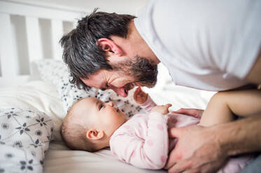 Father with a toddler girl on bed at home at bedtime. Paternity leave. - HPIF29645