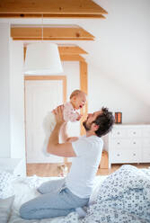 Father holding up a toddler girl in bedroom at home, having fun. Paternity leave. - HPIF29648