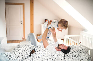 Reifer Vater mit einem kleinen Jungen, der sich im Schlafzimmer zu Hause vor dem Schlafengehen amüsiert. Vaterschaftsurlaub. - HPIF29651