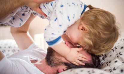 Reifer Vater mit einem Kleinkind, das sich im Schlafzimmer zu Hause vor dem Schlafengehen vergnügt. Vaterschaftsurlaub. Nahaufnahme. - HPIF29652