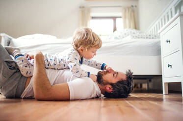 Reifer Vater mit einem kleinen Jungen, der sich im Schlafzimmer zu Hause vor dem Schlafengehen amüsiert. Vaterschaftsurlaub. - HPIF29656