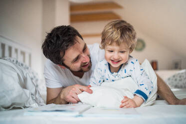Mature father with toddler boy in bedroom at home, reading stories at bedtime. Paternity leave. - HPIF29658
