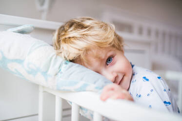 Ein glückliches Kleinkind in einem Kinderbettchen im Schlafzimmer zu Hause, Nahaufnahme. - HPIF29663