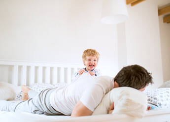 Reifer Vater mit einem kleinen Jungen, der sich im Schlafzimmer zu Hause vor dem Schlafengehen amüsiert. Vaterschaftsurlaub. - HPIF29667