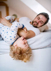 Reifer Vater mit einem kleinen Jungen, der sich im Schlafzimmer zu Hause vor dem Schlafengehen amüsiert. Vaterschaftsurlaub. - HPIF29668