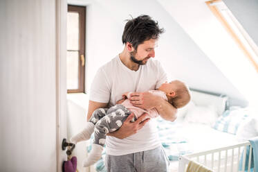 Reifer Vater trägt ein schlafendes Kleinkind im Schlafzimmer zu Hause. Vaterschaftsurlaub. - HPIF29680