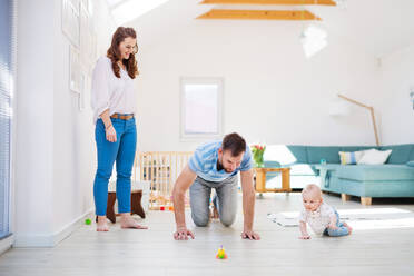 Junge Familie spielt mit einem kleinen Jungen zu Hause. Mutter, Vater und Sohn krabbeln auf dem Boden. - HPIF29691