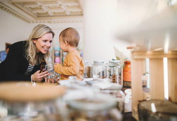 Eine attraktive junge Frau mit einem kleinen Jungen kauft in einem Zero-Waste-Laden Lebensmittel ein. - HPIF29711