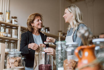 Eine junge Verkäuferin bedient einen älteren Kunden in einem Zero-Waste-Laden. - HPIF29748