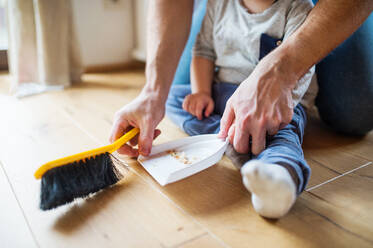 Unrecognizable father and toddler boy with brush and dustpan. Paternity leave. - HPIF29773