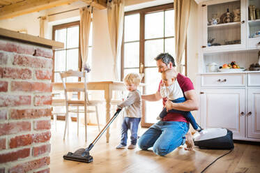 Vater und zwei Kleinkinder bei der Hausarbeit. Vaterschaftsurlaub. - HPIF29779