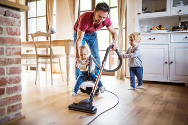 Vater und zwei Kleinkinder bei der Hausarbeit. Vaterschaftsurlaub. - HPIF29780