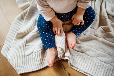 Unrecognizable little toddler at home, sitting on the floor. - HPIF29798