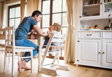 Ein Vater, der mit einem kleinen Jungen zu Hause am Tisch sitzt. Vaterschaftsurlaub. - HPIF29809