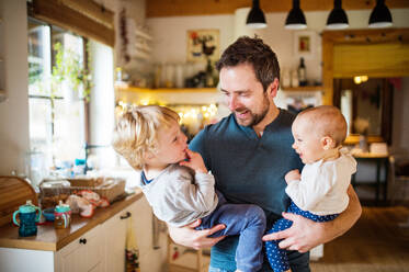Father holding two toddlers at home. Paternity leave. - HPIF29814
