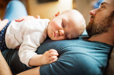 Vater mit einem kleinen Mädchen zu Hause, das auf dem Sofa schläft, Vaterschaftsurlaub, Nahaufnahme. - HPIF29821