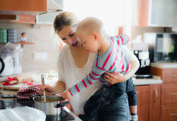 Ein behinderter Junge mit Down-Syndrom kocht mit seiner Mutter im Haus eine Suppe zum Abendessen oder Mittagessen. - HPIF29858