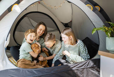 Glückliche Familie mit Vizsla-Hund beim Spielen im Zelt zu Hause - NDEF00635