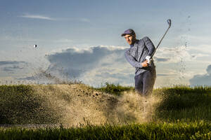 Mann spielt Golf stehend auf Gras - STSF03717