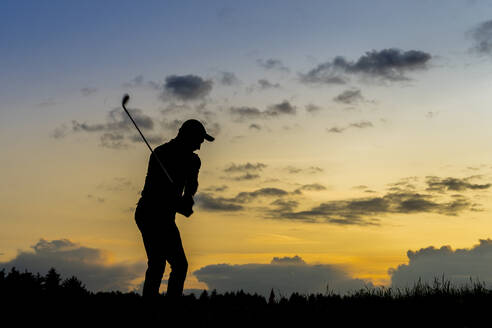 Silhouette eines Mannes beim Golfspielen in der Abenddämmerung - STSF03725