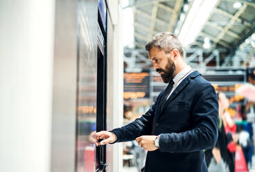 Hipster Geschäftsmann kauft eine Fahrkarte in einem Automaten in der U-Bahn-Station. Raum kopieren. - HPIF29936