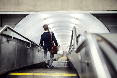 Rückansicht eines Hipster-Geschäftsmannes, der in der U-Bahn in der Stadt die Treppe hinuntergeht und zur Arbeit fährt. - HPIF29937