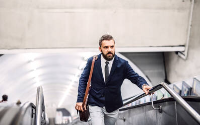 Happy hipster businessman using escalator in subway, travelling to work. - HPIF29938