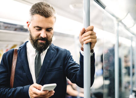 Hipster Geschäftsmann mit Smartphone sitzt in der U-Bahn in der Stadt, auf dem Weg zur Arbeit. - HPIF29944