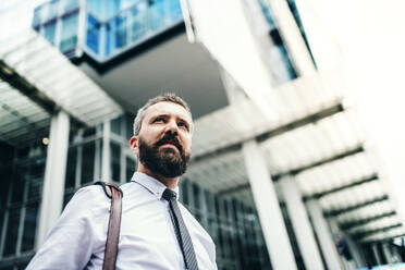 Low angle portrait of businessman standing on the street in city in front of a building. copy space. - HPIF29947