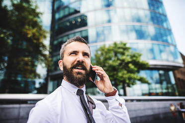 A close-up of hipster businessman with smartphone in the city, making a phone call. Copy space. - HPIF29960