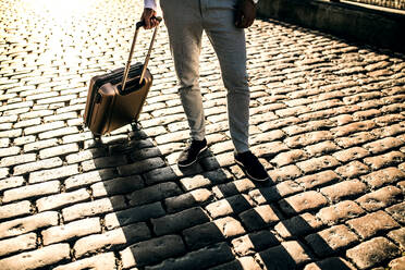 Legs of businessman with suitcase standing on a pavement on the street. Copy space. - HPIF29999