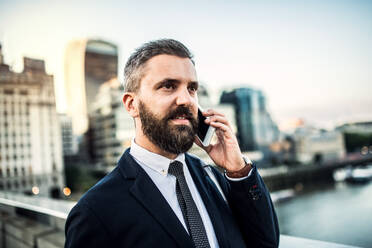 A close-up of hipster businessman with smartphone in the city, making a phone call. Copy space. - HPIF30045