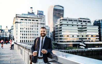 Seriöser Hipster mit Geschäftsmann mit Kaffee und Smartphone im Freien stehend in der Stadt, Textnachrichten. - HPIF30047