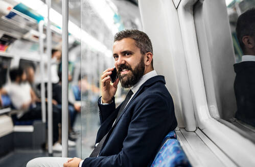 Hipster Geschäftsmann mit Smartphone sitzt in der U-Bahn in der Stadt, auf dem Weg zur Arbeit. - HPIF30053