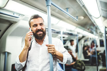 Hipster Geschäftsmann mit Smartphone steht in der U-Bahn in der Stadt, auf dem Weg zur Arbeit und macht einen Anruf. - HPIF30074