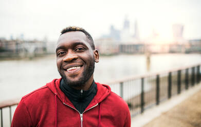 A close-up of black man runner standing in a city. Copy space. - HPIF30142