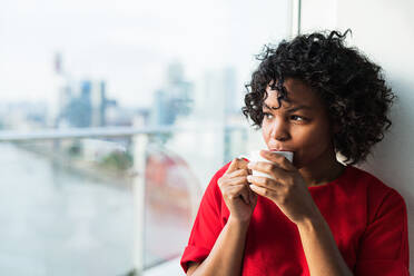 A close-up of a woman standing by the window drinking coffee. Copy space. - HPIF30172