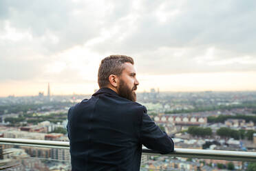 Rückansicht eines Hipster-Geschäftsmannes vor dem Panorama von London. - HPIF30251