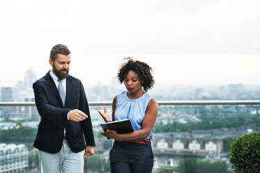 A portrait of businesspeople standing against London rooftop view, discussing something. - HPIF30259