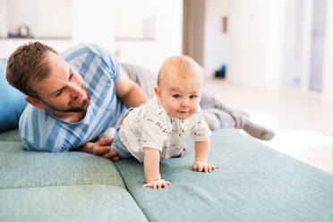 Handsome young father with a baby son at home, having fun on the sofa. - HPIF30291