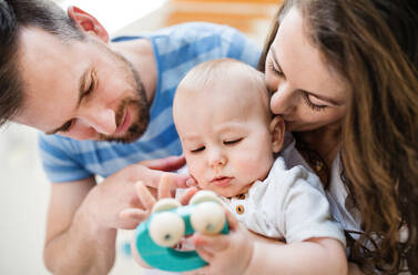 Porträt einer jungen Familie und eines kleinen Jungen mit einem Holzspielzeug zu Hause, Nahaufnahme. - HPIF30293