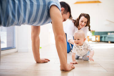 Young family with a baby boy at home, having fun. Father, mother and a son crawling on the floor. - HPIF30299